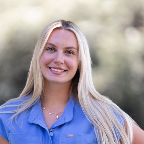 Stephanie, a Customer Service Representative at Mid-Valley Veterinary Hospital, smiling outdoors in blue scrubs.